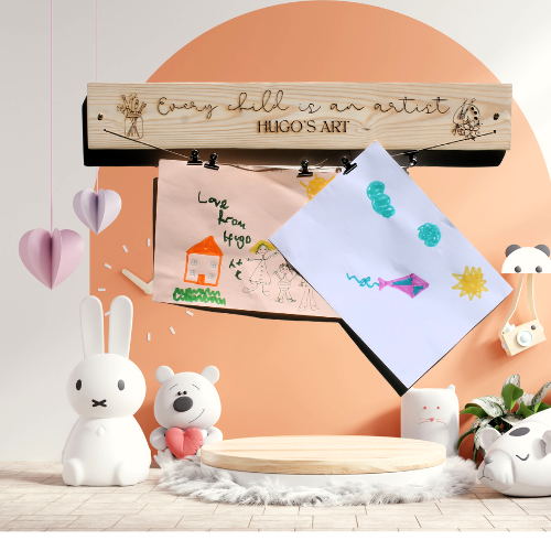 Wooden art display with children's drawings and decorative items on a peach-colored wall.