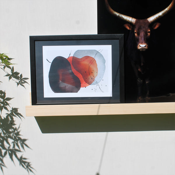 wooden picture gallery shelf used to display a picture of a bull and an abstract black and rust picture