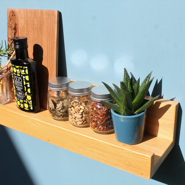 floating shelf made of wood used as a spice rack and showing kitchen ingredients storage and a plant