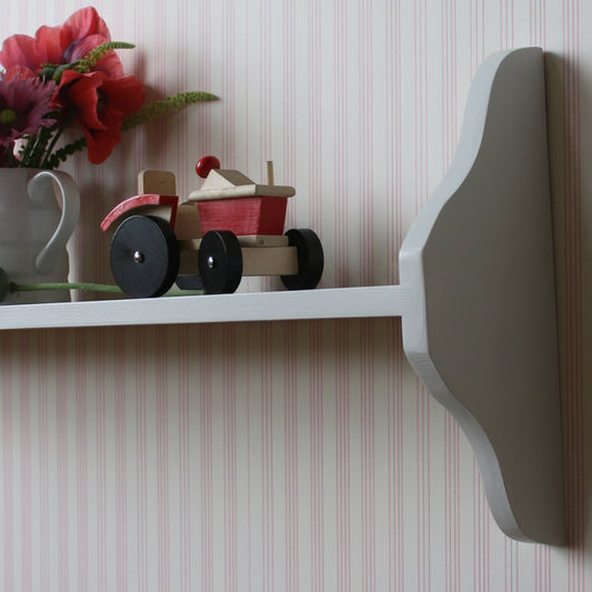 A painted one tiere shelf in cottage core style with a vase with flowers and a toy tractor on top