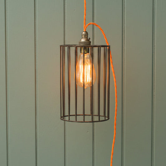a steampunk lampshade with orange cable set against a grey wall